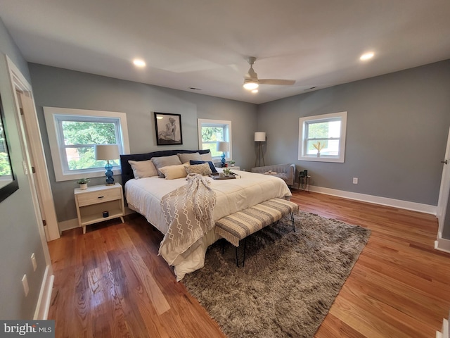 bedroom with multiple windows, hardwood / wood-style floors, and ceiling fan