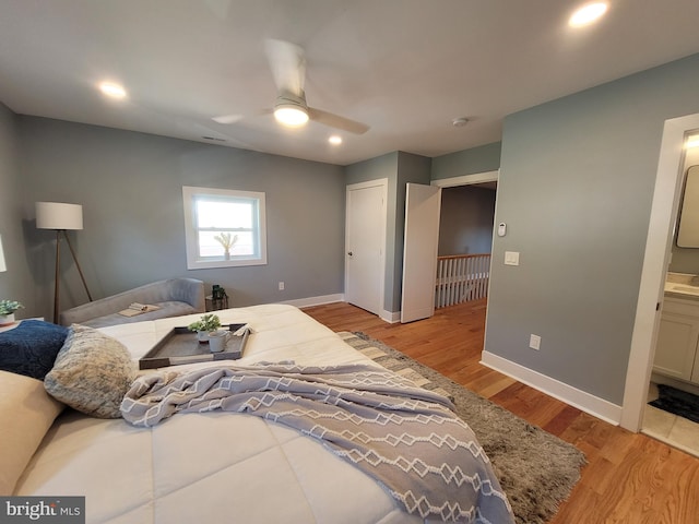 bedroom with ceiling fan, ensuite bath, and light hardwood / wood-style floors