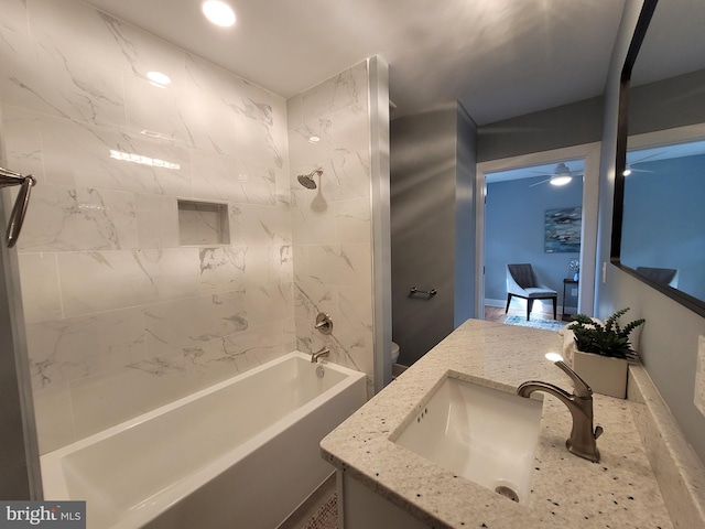 full bathroom featuring vanity, tiled shower / bath, and toilet