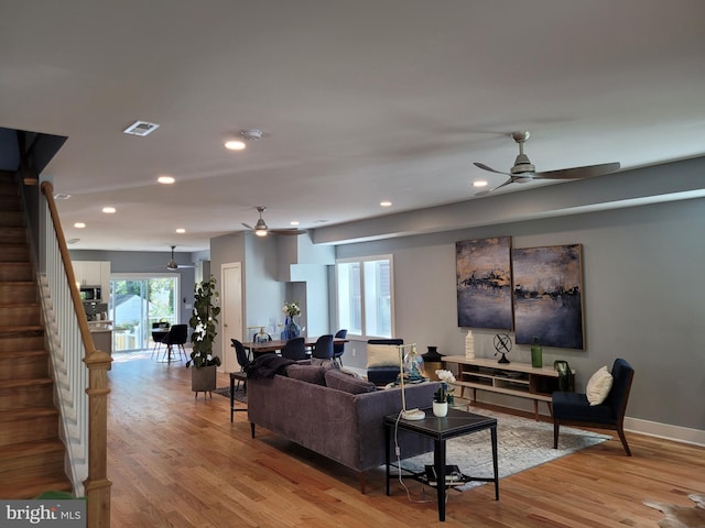 living room with light hardwood / wood-style floors and ceiling fan