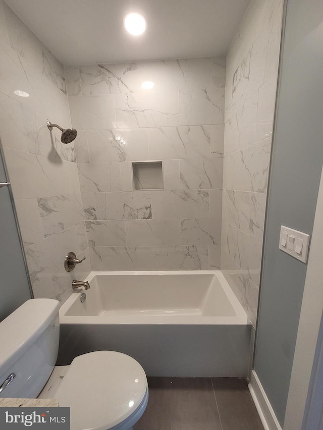 bathroom with tiled shower / bath combo and toilet