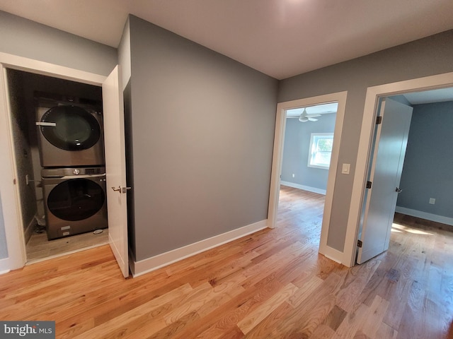 laundry area with stacked washer and clothes dryer and light hardwood / wood-style floors