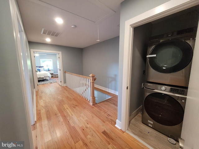 washroom featuring stacked washer and clothes dryer and light hardwood / wood-style flooring