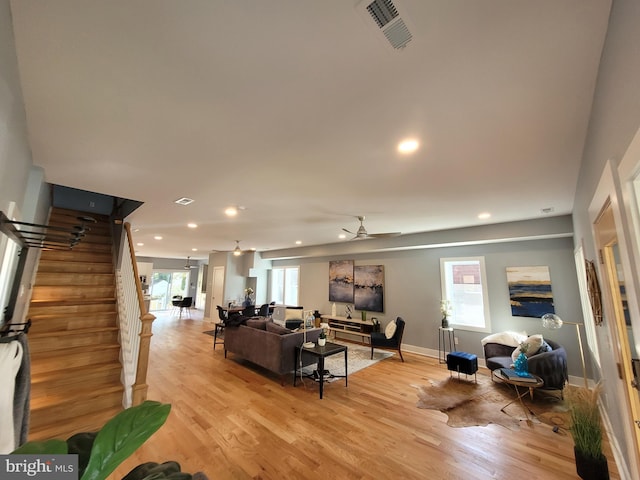 living room with light wood-type flooring, ceiling fan, and a healthy amount of sunlight