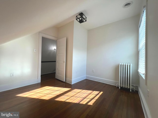 additional living space with lofted ceiling, dark hardwood / wood-style floors, and radiator heating unit