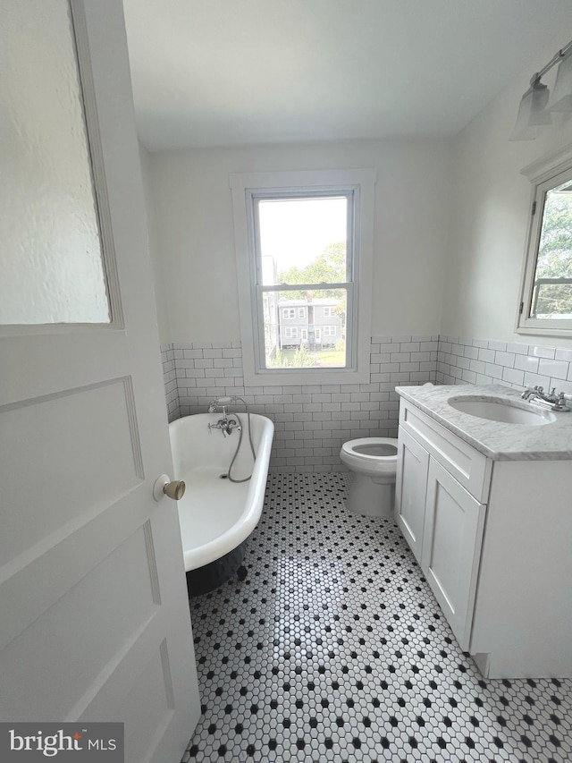 bathroom featuring a healthy amount of sunlight, a bathing tub, and tile walls