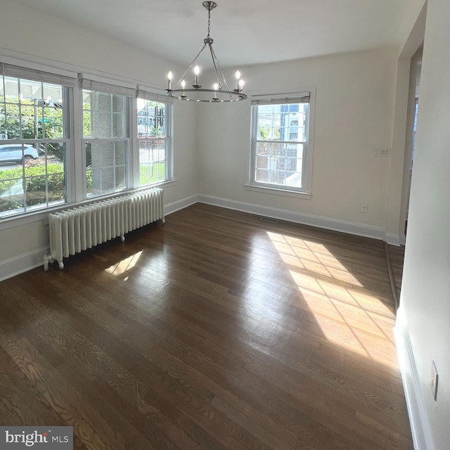 unfurnished dining area with dark hardwood / wood-style floors, radiator, and a notable chandelier