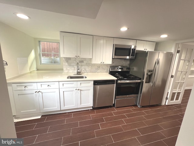 kitchen with appliances with stainless steel finishes, dark hardwood / wood-style floors, tasteful backsplash, sink, and white cabinets