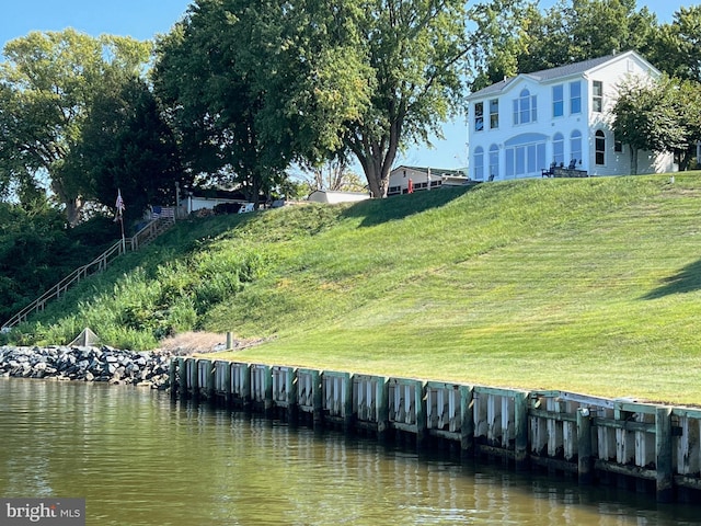 view of dock with a water view and a lawn