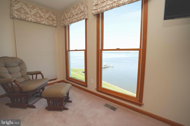 living area with a water view and carpet