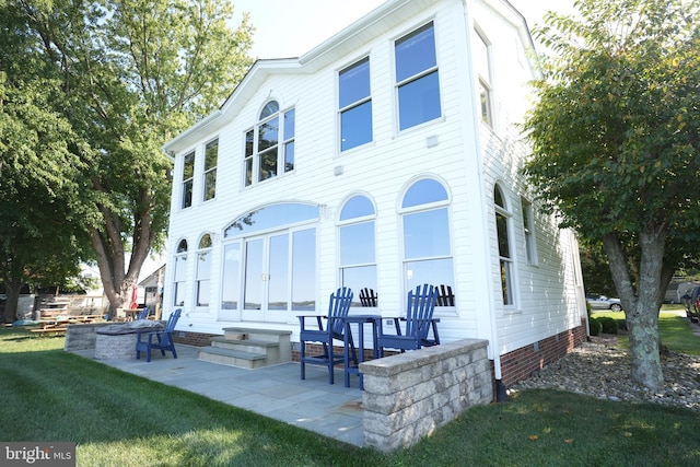 rear view of house featuring a lawn, a patio area, and an outdoor fire pit