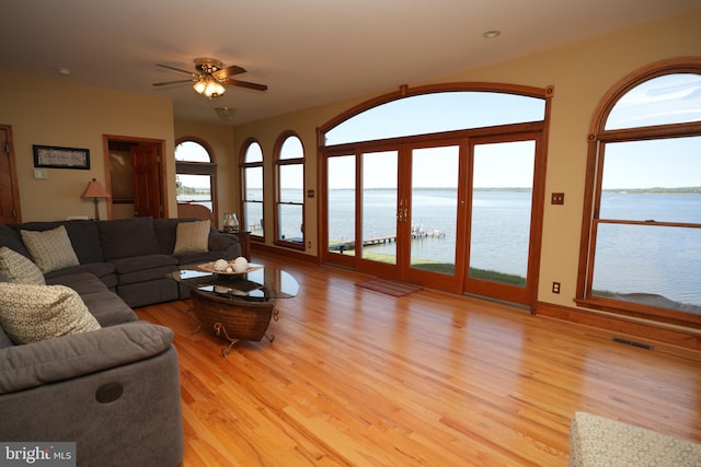 living room with a water view, light wood-type flooring, and ceiling fan