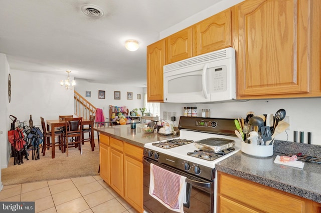 kitchen featuring range, light brown cabinets, a chandelier, light colored carpet, and dark stone counters