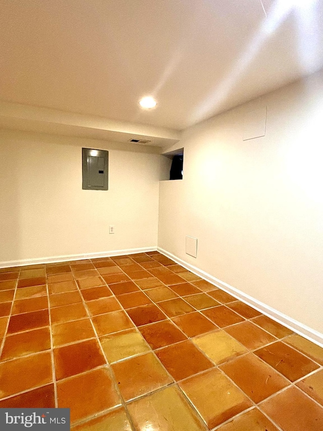 basement featuring electric panel and tile patterned flooring