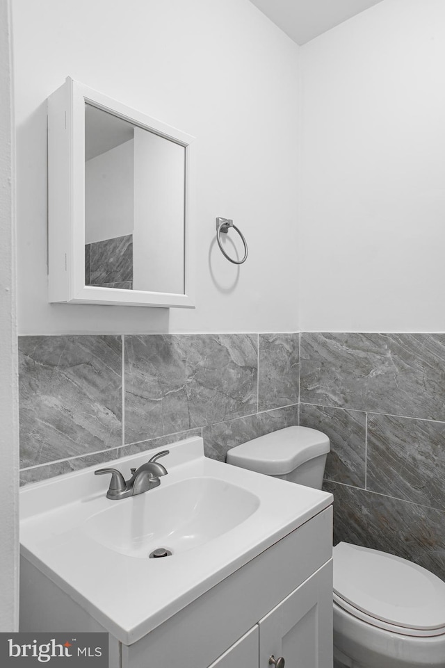 bathroom featuring tile walls, toilet, and vanity