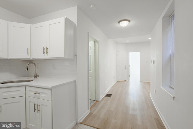 hallway with light wood-type flooring and sink