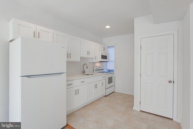 kitchen featuring white appliances, sink, white cabinets, and decorative backsplash