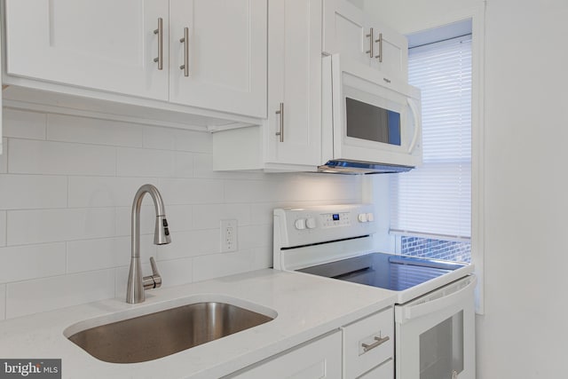 kitchen featuring white cabinets, white appliances, light stone countertops, sink, and tasteful backsplash