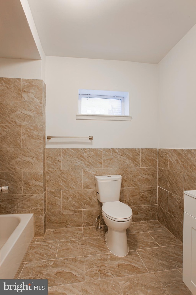 bathroom with vanity, toilet, tile walls, and a washtub