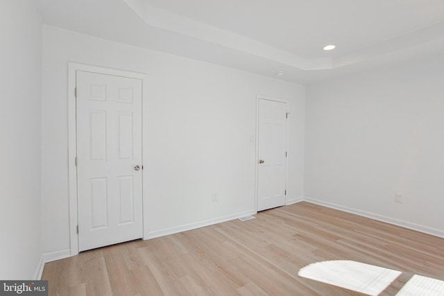 interior space with a raised ceiling and light hardwood / wood-style floors