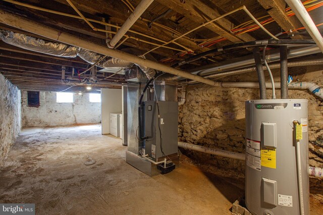 basement with washer and dryer, heating unit, and electric water heater