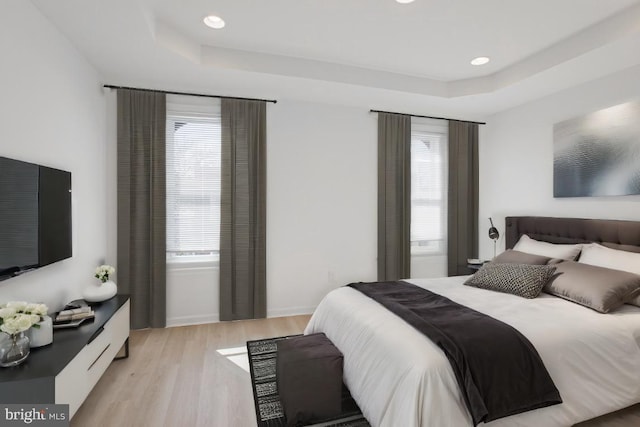 bedroom with a raised ceiling and light hardwood / wood-style floors