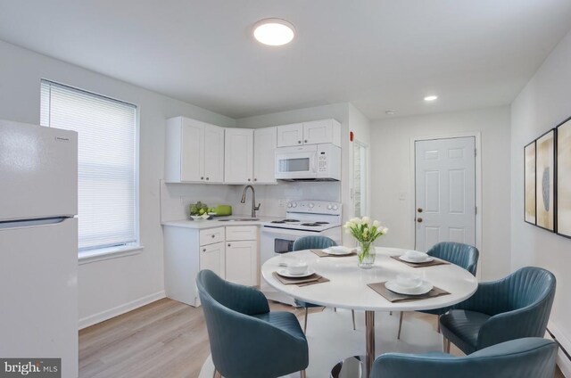 kitchen with white appliances, a wealth of natural light, white cabinets, and light hardwood / wood-style floors