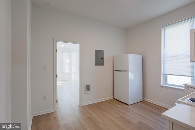 interior space with white refrigerator, electric panel, light hardwood / wood-style floors, and heating unit