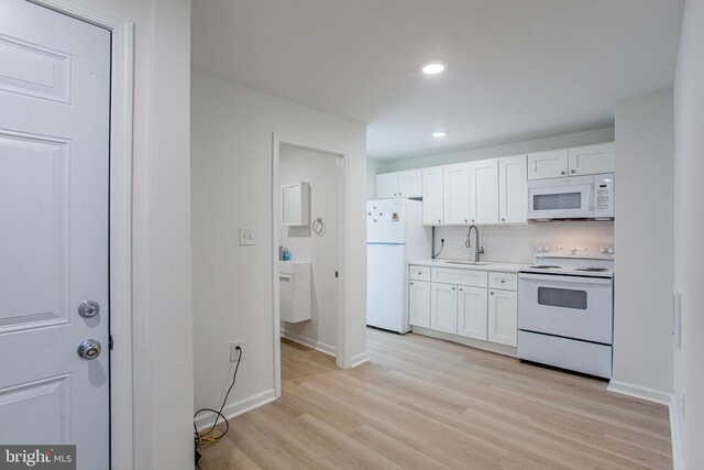 kitchen featuring white cabinetry, white appliances, light hardwood / wood-style flooring, and sink