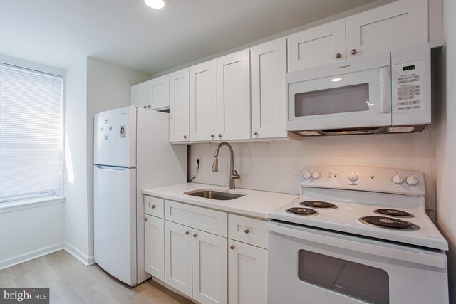 kitchen with white cabinets, white appliances, light hardwood / wood-style floors, sink, and decorative backsplash