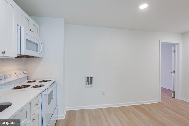 kitchen with light wood-type flooring, white appliances, light stone countertops, and white cabinets