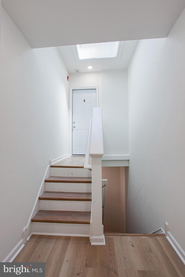 stairway featuring hardwood / wood-style flooring and a skylight