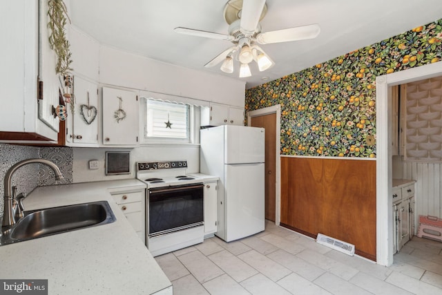 kitchen featuring white cabinetry, white appliances, wood walls, sink, and ceiling fan