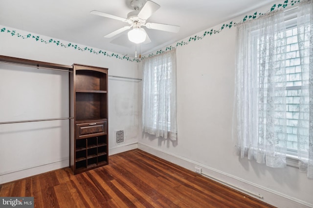 interior space featuring multiple windows, dark hardwood / wood-style flooring, and ceiling fan