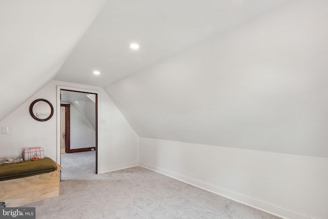 additional living space featuring light carpet and vaulted ceiling