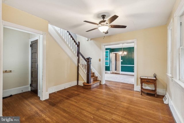 interior space with ceiling fan with notable chandelier and hardwood / wood-style floors