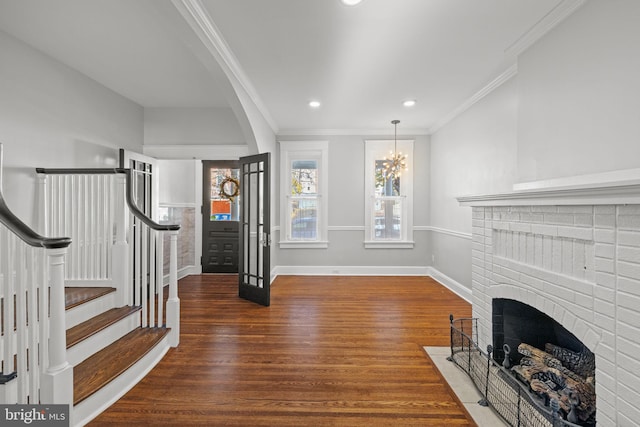 living room with ornamental molding, an inviting chandelier, dark hardwood / wood-style floors, and a fireplace