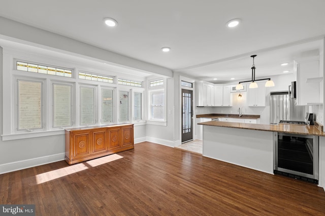 kitchen featuring white cabinets, kitchen peninsula, dark hardwood / wood-style floors, and beverage cooler