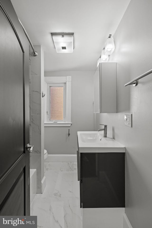 bathroom with toilet, vanity, and a tile shower