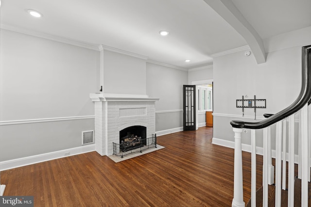 unfurnished living room with a brick fireplace, dark wood-type flooring, and ornamental molding