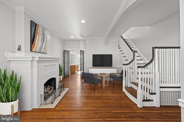 living room with dark wood-type flooring, a fireplace, and ornamental molding