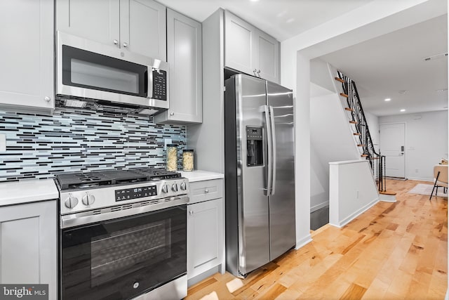 kitchen featuring stainless steel appliances, light wood-type flooring, and tasteful backsplash