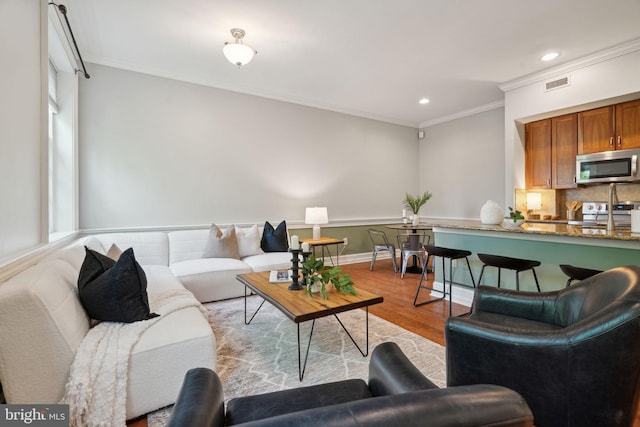 living room featuring light wood-type flooring, plenty of natural light, and ornamental molding