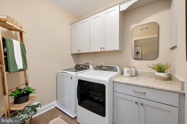 clothes washing area featuring dark hardwood / wood-style flooring, cabinets, and washing machine and dryer