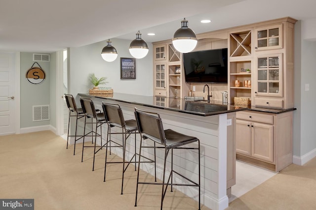 bar featuring hanging light fixtures, light colored carpet, and sink