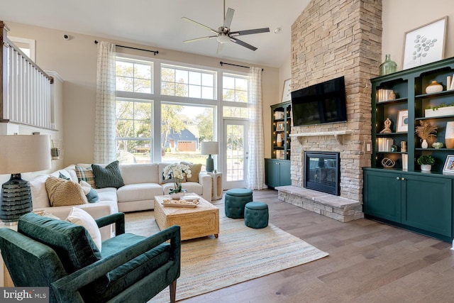 living room featuring hardwood / wood-style flooring, plenty of natural light, ceiling fan, and a stone fireplace