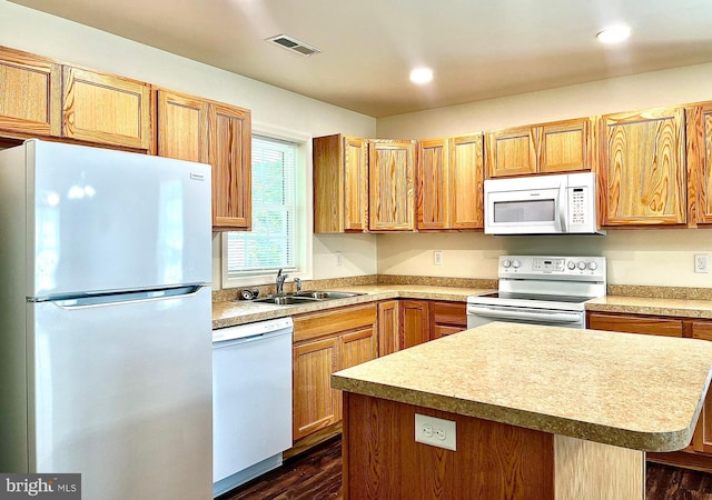 kitchen featuring sink, dark wood-type flooring, white appliances, and a kitchen island