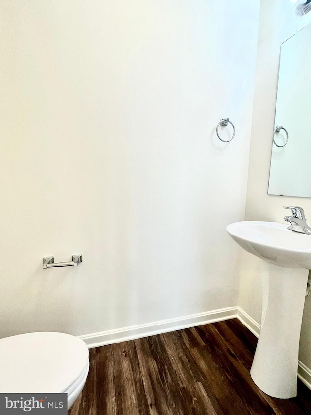 bathroom with wood-type flooring, toilet, and sink