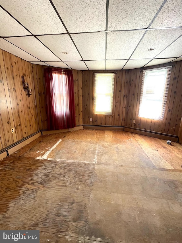 unfurnished room with a paneled ceiling and wood walls