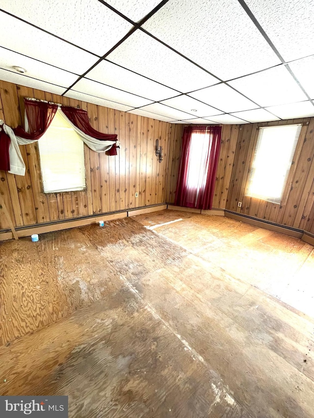 interior space with a paneled ceiling and wooden walls